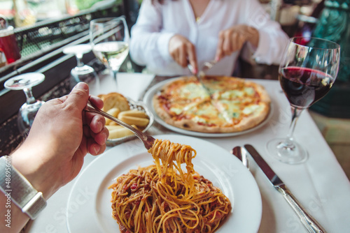 couple eating in restaurant pasta and pizza drinking wine