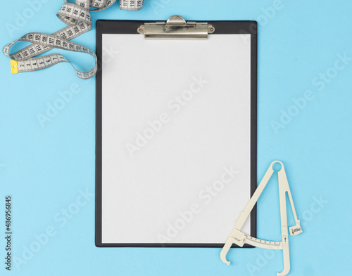 A tablet with a blank page on a blue background with hand. Medical diagnosis or a mock-up of a doctor's prescription.