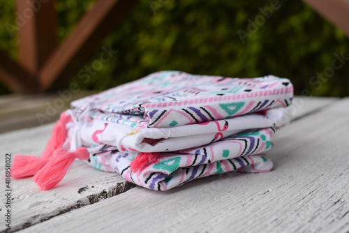 Small pile of colorful baby clothes, on white wooden background