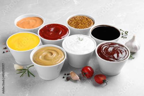 Many bowls with different sauces on light grey table