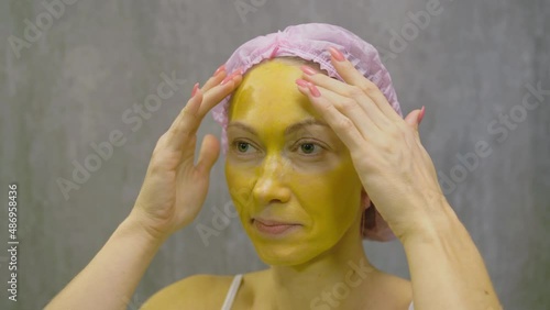 Procedure for skin care to face of young pretty woman. Beauty salon, facial peeling yellow gold alginate mask with retinol treatment, fruit acids. Apply mask on face of model. Cosmetology therapy. photo