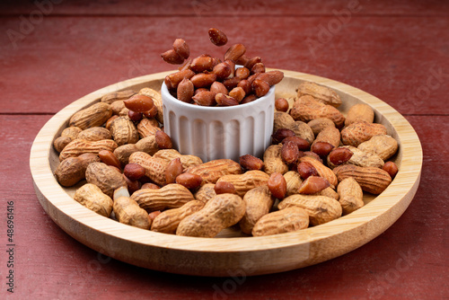 Peanuts falling into a snack bar, on a red wooden table.