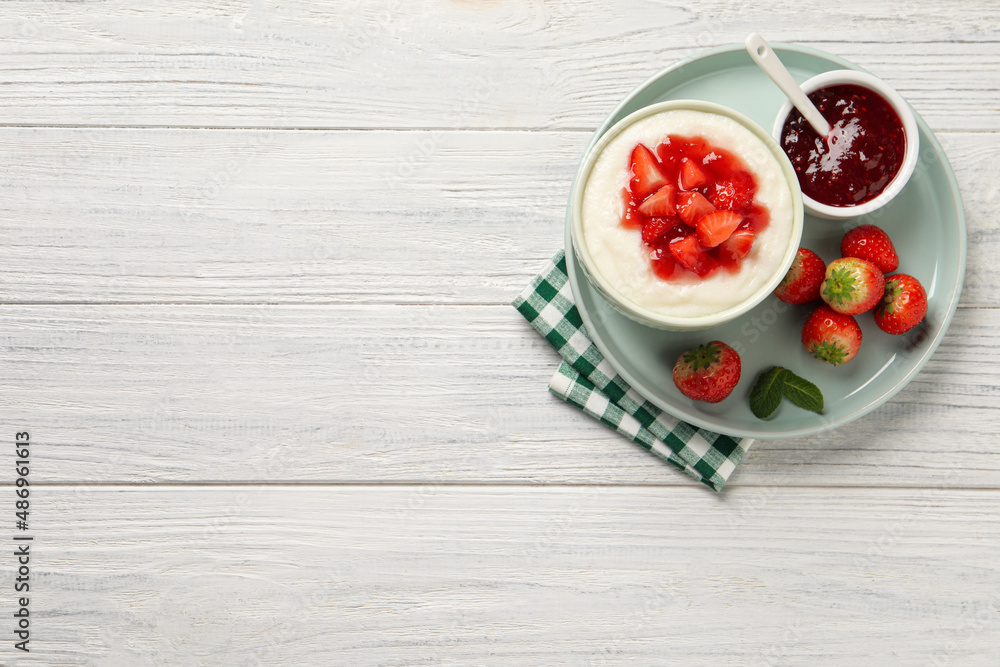 Delicious semolina pudding with strawberries and jam on white wooden table, top view. Space for text Delicious semolina pudding with strawberries and jam on white wooden table, top view. Space for text