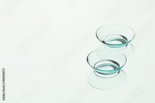 Pair of contact lenses on white reflective surface. Space for text