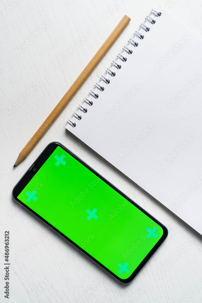 White blank notepad smartphone green screen mockup and pencil flat lay. Tamplate for design White blank notepad smartphone green screen mockup and pencil flat lay. Tamplate for design