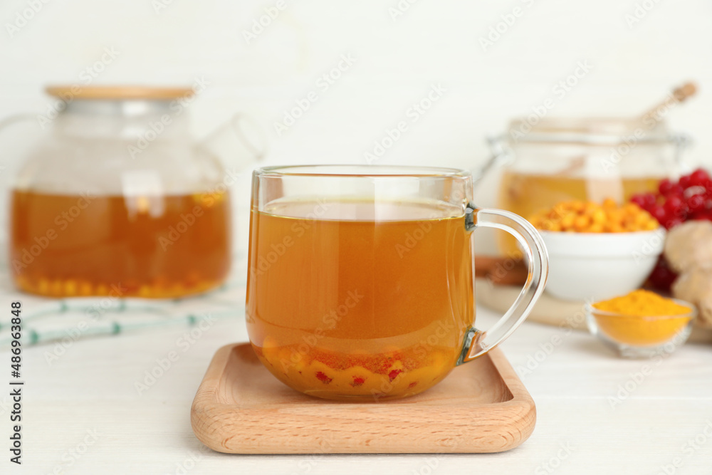 Glass cup of immunity boosting tea with ingredients on white wooden table Glass cup of immunity boosting tea with ingredients on white wooden table
