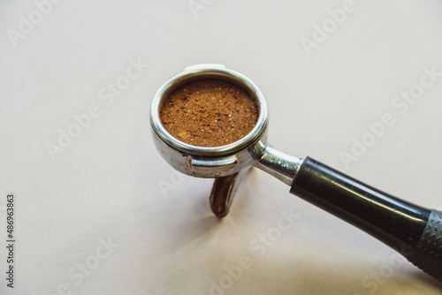 Portafilter with ground coffee on a light gray background. Top view