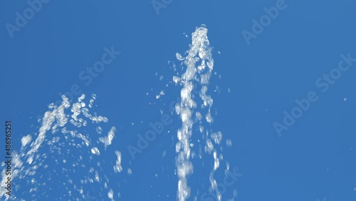 Two white fountain jets against a blue sky. Slow motion water. The upward movement of water. Spray from the fountain. natural texture