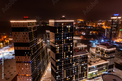 An aerial view of new residential area with apartment buildings and shopping mall lit up by evening illumination