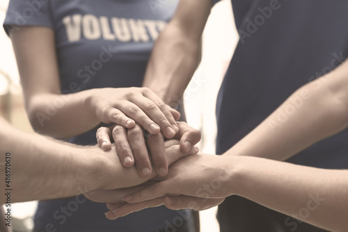 Group of volunteers joining hands together, closeup. Black and white effect