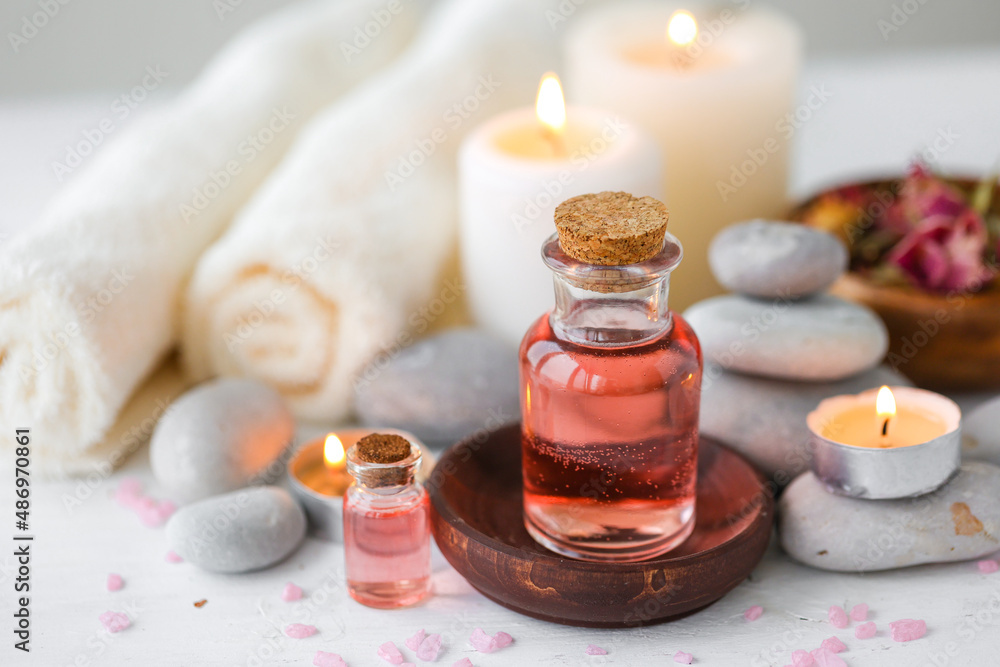 Concept of spa treatment in salon. Natural organic oil, towel, candles as decor. Atmosphere of relax, serenity and pleasure. Anti-stress and detox procedure. Luxury lifestyle. White wooden background Concept of spa treatment in salon. Natural organic oil, towel, candles as decor. Atmosphere of relax, serenity and pleasure. Anti-stress and detox procedure. Luxury lifestyle. White wooden background