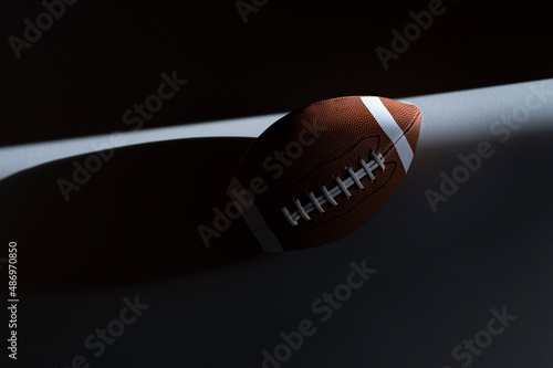 American football ball with natural lighting on dark background. Horizontal sport theme poster, greeting cards, headers, website and app