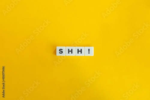 Shh volitive interjection. Letter tiles on bright orange background. Minimal aesthetics. photo