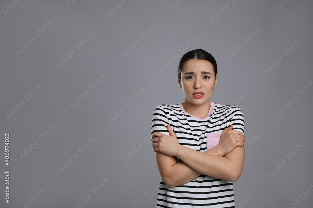 Obraz premium Young woman suffering from fever on grey background, space for text. Cold symptoms