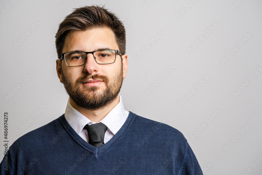 Portrait of one adult caucasian man 30 years old with beard and eyeglasses looking to the camera in front of white wall background wearing sweater young businessman success concept copy space Portrait of one adult caucasian man 30 years old with beard and eyeglasses looking to the camera in front of white wall background wearing sweater young businessman success concept copy space