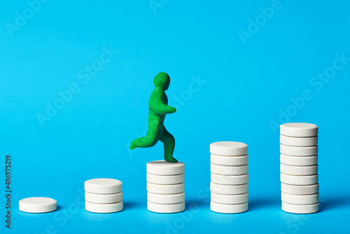 the concept of increasing the dose of drugs. The plasticine figure of a man climbs a ladder of pills
