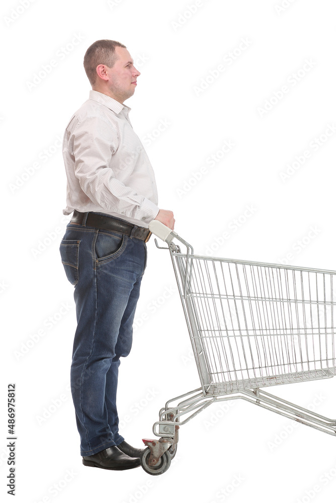 Full length side view of handsome young man standing with shopping trolley and looking at camera Full length side view of handsome young man standing with shopping trolley and looking at camera