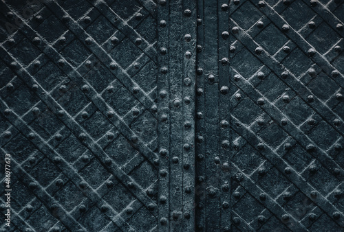 Old black metal door with a diamond pattern. Vintage background closeup. Medieval forging technologies.