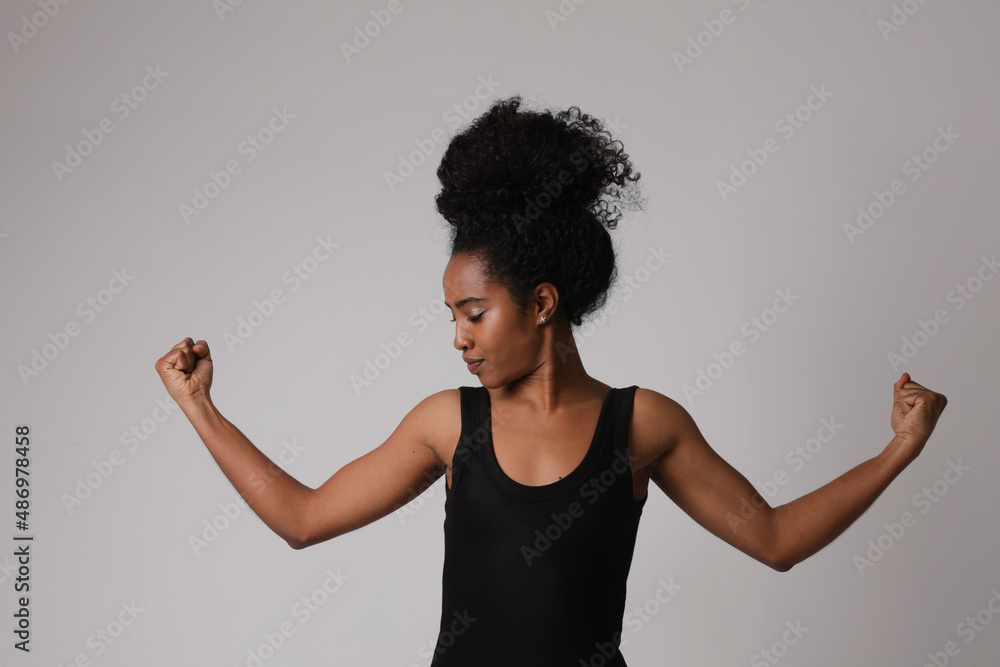 Confident black afro young woman shows her biceps, she is strong and powerful. Confident black afro young woman shows her biceps, she is strong and powerful.