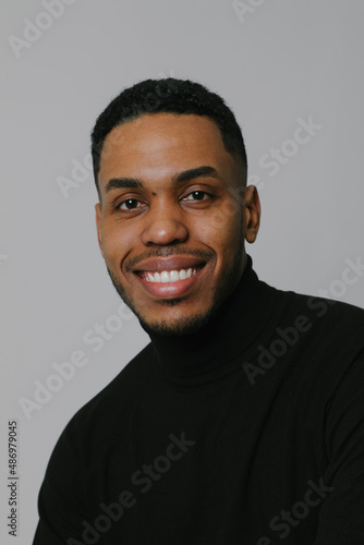 Portrait of millennial African American man posing over white wall. Vertical.