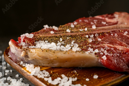 Raw T-bone steak cooking on stone table