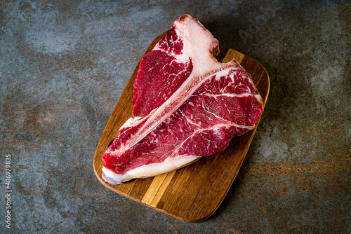 Raw T-bone steak cooking on stone table. Top view with copy space