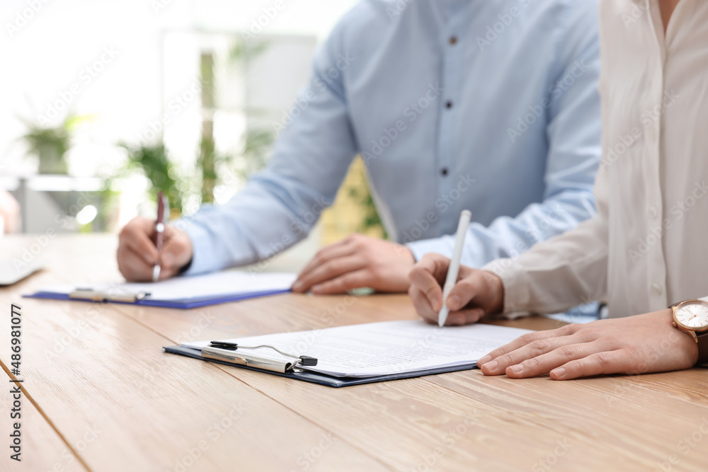 Woman signing contract at table in office, closeup. Woman signing contract at table in office, closeup.