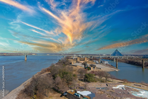 a aerial shot of Mud Island, Wolf Creek harbor and the flowing waters of the Mississippi river with the Hernando de Soto Bridge over the water with blue sky and powerful clouds in Memphis Tennessee photo