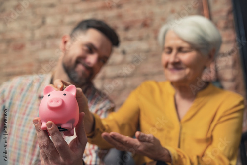 Φωτογραφία successful caucasian businessman learning his grandmother to save money using piggy bank