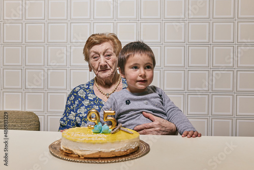 great-granddaughter and great-grandmother almost centenarian celebrating her birthday with joy. Concept of family, generational change photo