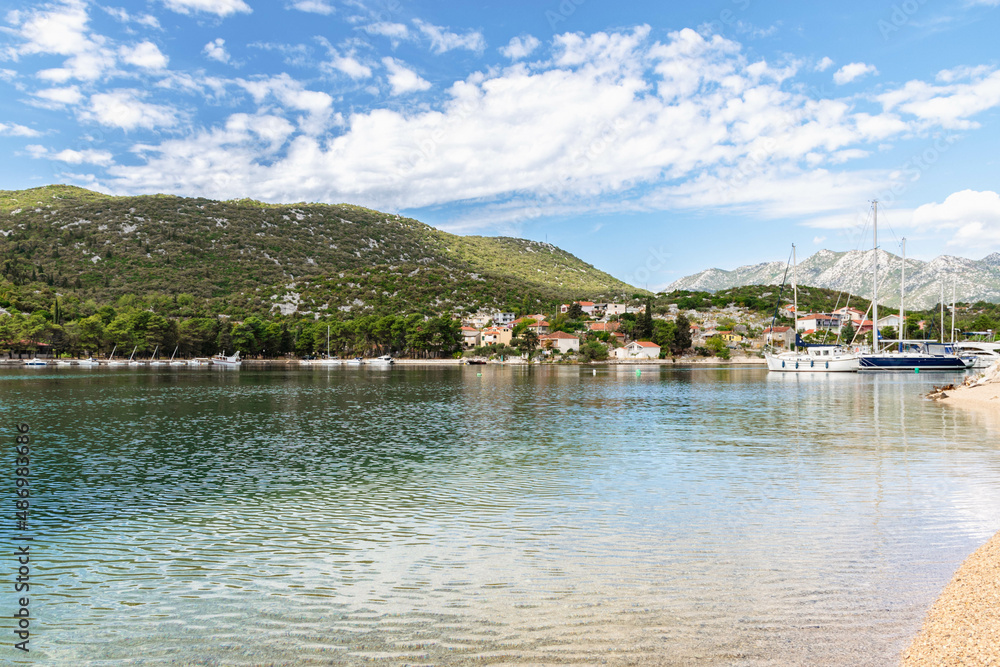 bay in Ploce in Croatia, summer day in a holiday resort in Croatia, clear water, boats in ploce harbor, green hills in the mediterranean part of Croatia, Dalmatia