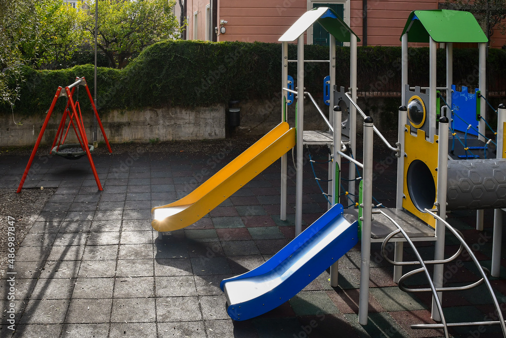 High-angle view of an empty children playground with slides and swing, Italy