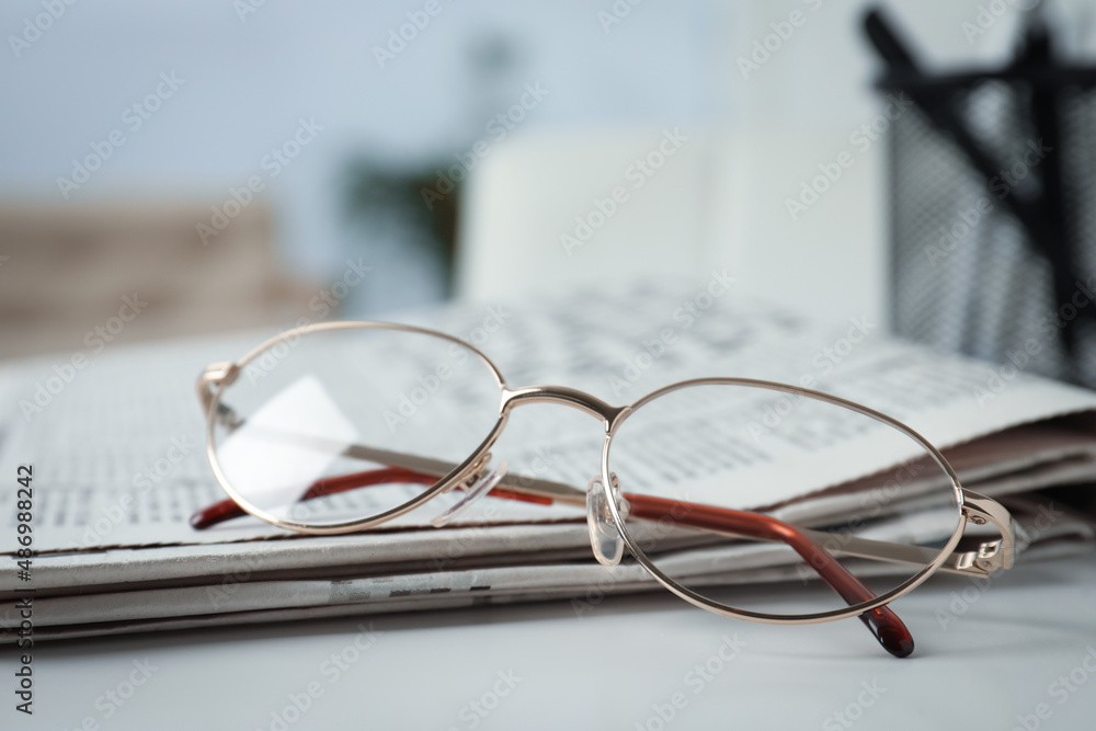 Stack of newspapers and glasses on white table indoors, closeup Stack of newspapers and glasses on white table indoors, closeup