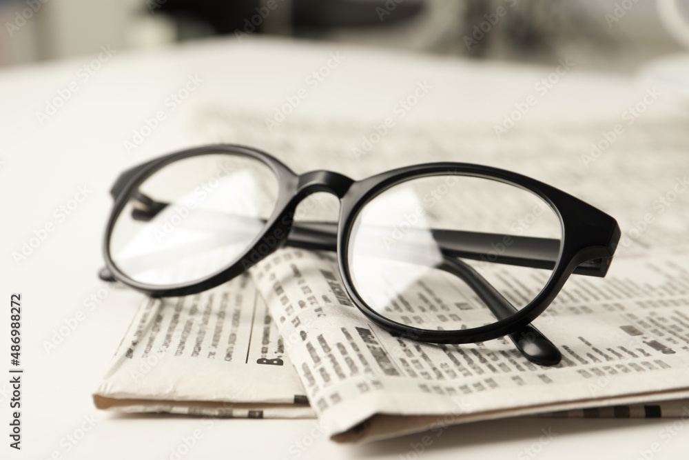 Newspapers and glasses on white table, closeup Newspapers and glasses on white table, closeup