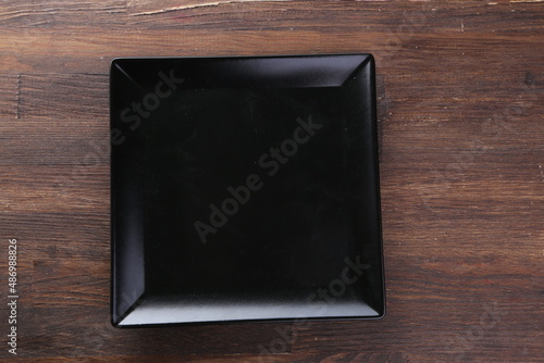 Elegant black table setting: plate, napkin and silverware over dark background. Flat lay. Top view.