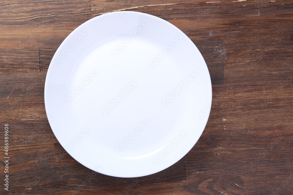 empty plate waiting for food, sitting on wooden table, top view, copy space. Hunger and lunch time concept empty plate waiting for food, sitting on wooden table, top view, copy space. Hunger and lunch time concept