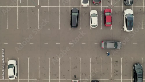 Cars arrive at the parking lot and park in free spaces. Car pass throw the parking lot. Car leaves the parking lot - aerial top overhead drone shot.