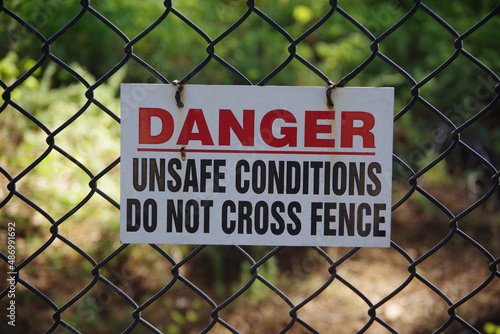 Sign on a fence DANGER - UNSAFE CONDITIONS - DO NOT CROSS FENCE