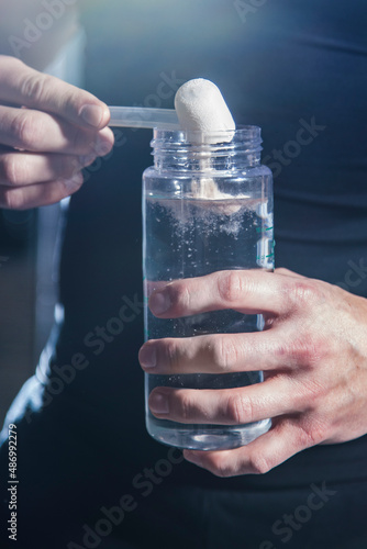 Pre Workout protein powder being poured into water bottle by athlete