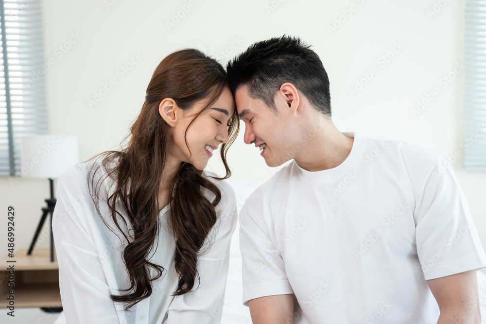 Portrait of Asian young couple sitting on bed and look at each other. Portrait of Asian young couple sitting on bed and look at each other.