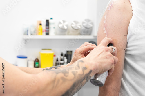 Tattoo process  Tattooist applying gel to client arm. High quality photo