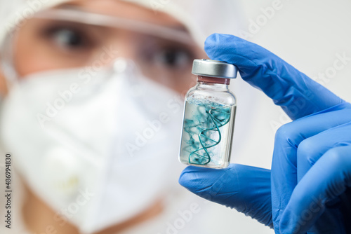 Coronavirus vaccine concept,UK doctor medical lab scientist holding glass phial ampoule containing COVID-19 vaccine