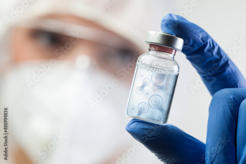 Cell division process conceptual illustration,lab scientist holding ampoule vial with DNA cell nucleus molecules splitting