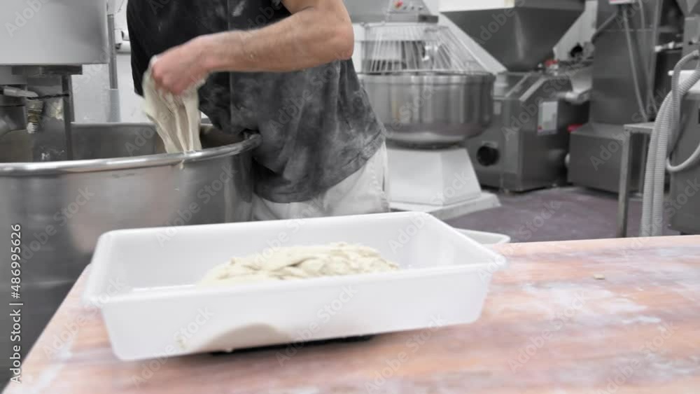 Baker taking out dough of a kneading machine at industrial bakery. High quality 4k footage Baker taking out dough of a kneading machine at industrial bakery. High quality 4k footage