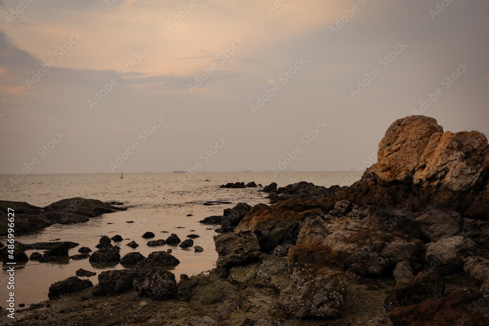 Rocky sea shore against sunset scape.