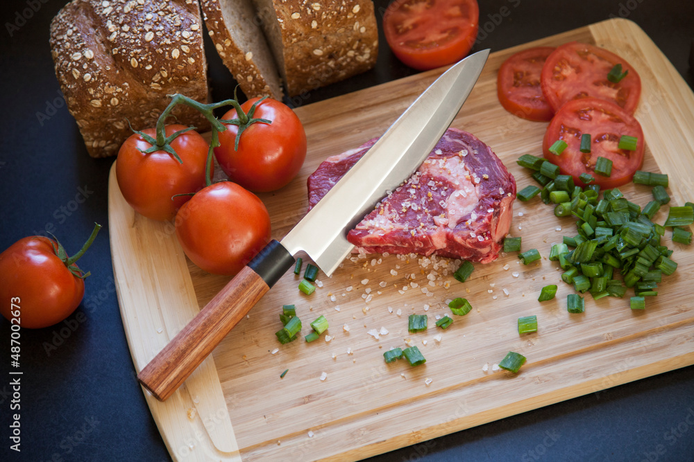 Solid Steel professional chef knife on wooden counter cutting board with freshly chopped fruits, vegetables, meet, and bread Solid Steel professional chef knife on wooden counter cutting board with freshly chopped fruits, vegetables, meet, and bread