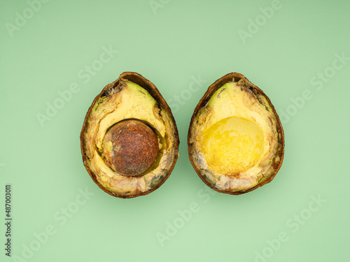 Fotografi Rotten avocado cut in half over a green background