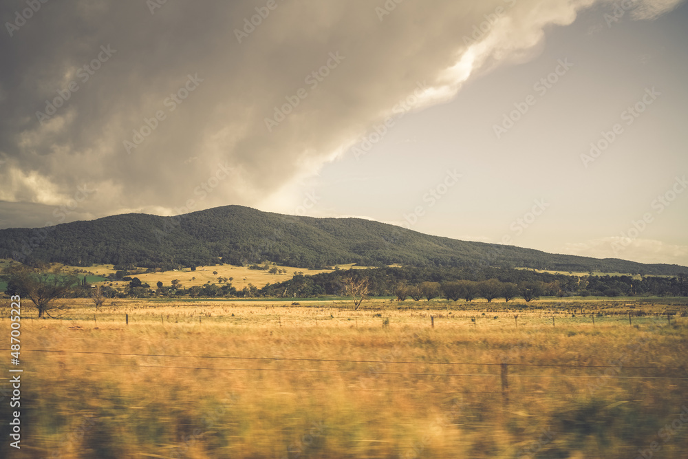 Fototapeta premium Mountains behind fields of golden grass