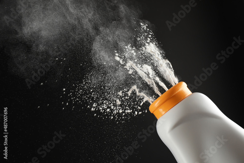 Scattering of dusting powder on black background photo