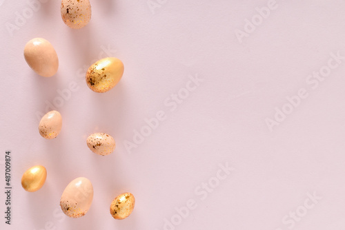 Various Easter eggs of yellow shades lie on a pink background. Copy space. Flat lay, top view